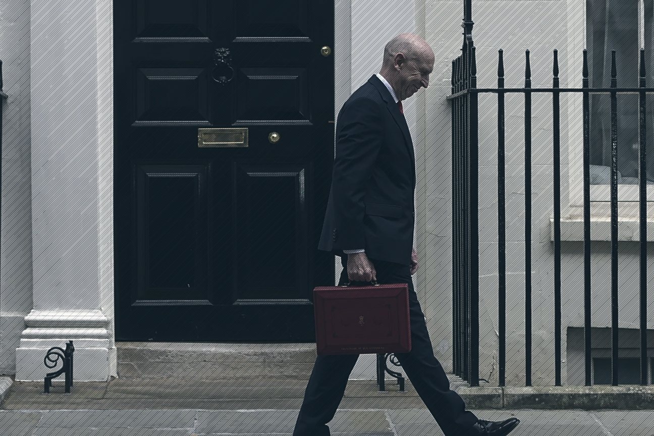 John Healey walks past a black Downing Street door carrying the red budget box
