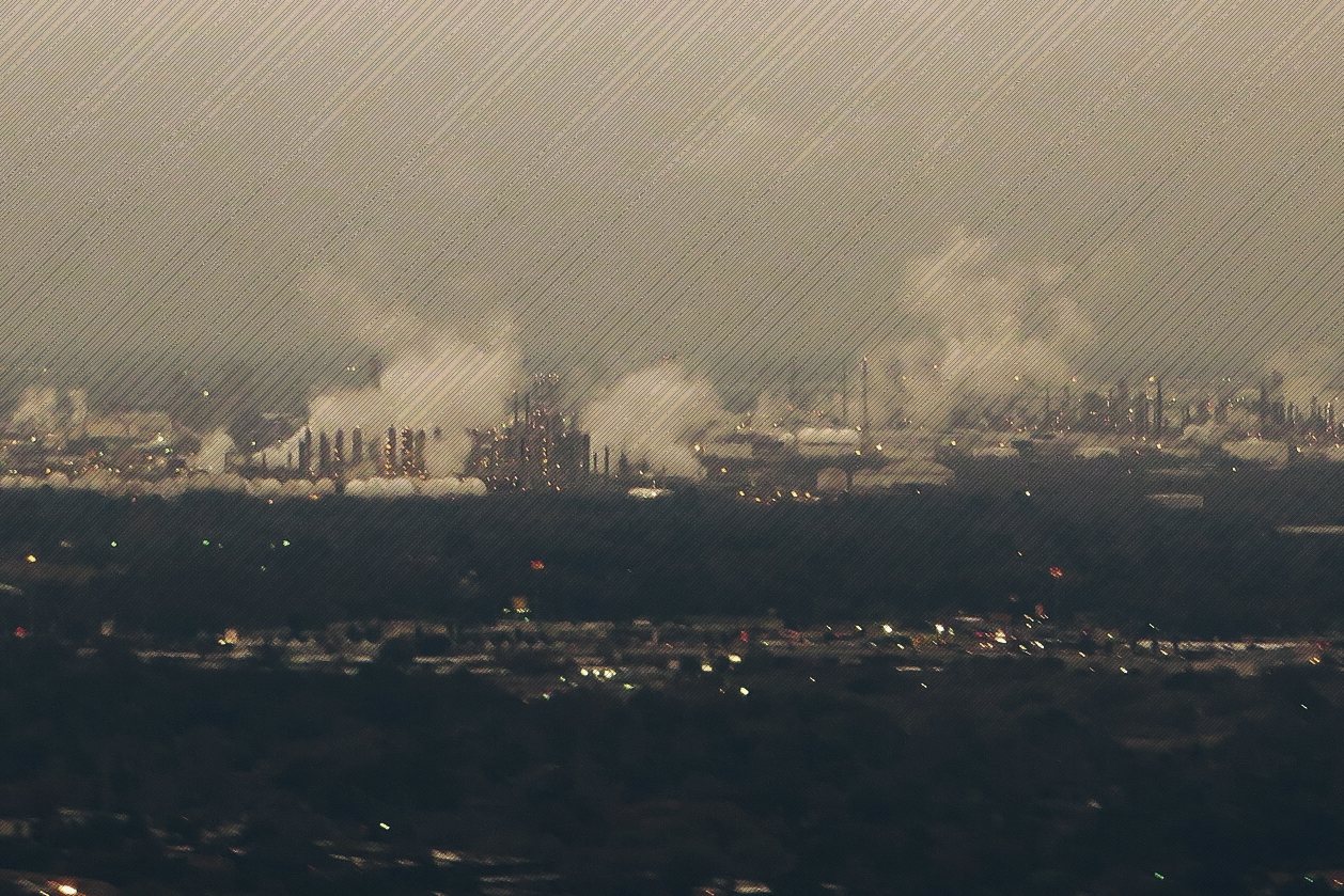 Refinery stacks and steam plumes across the Houston skyline at dusk