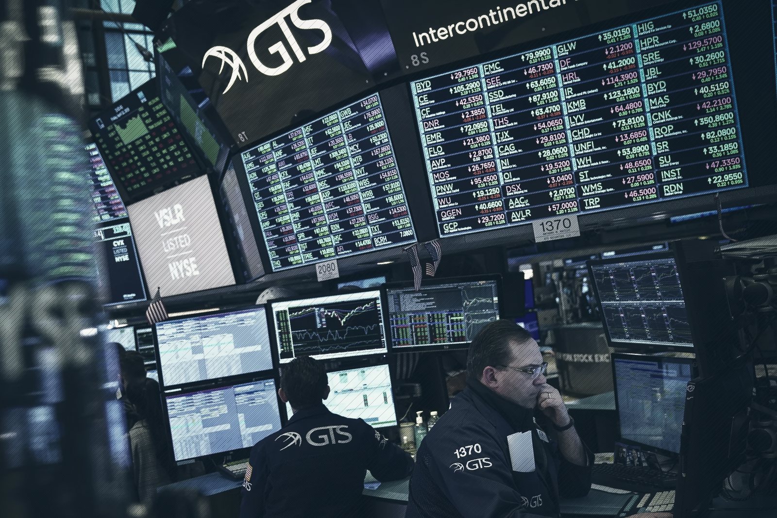 Traders work beneath banks of screens showing share prices on the floor of the New York Stock Exchange